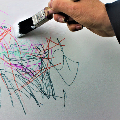 man applying primer over a child's scribbles on a wall