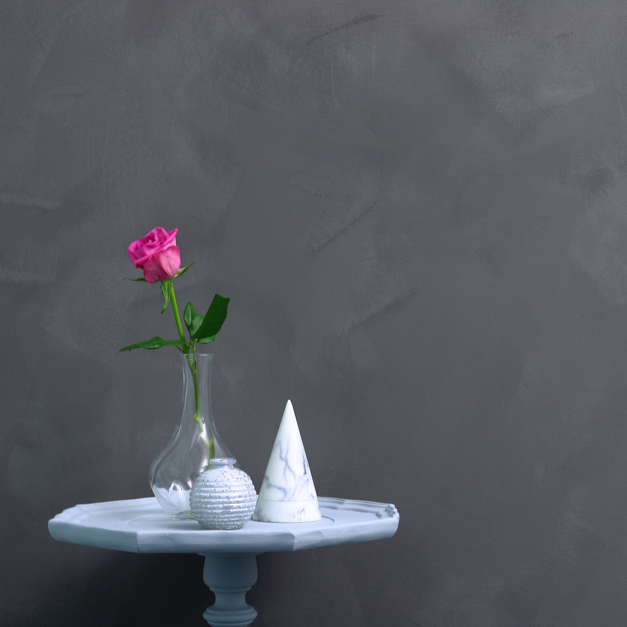 painted side table, decorated with ornaments, in front of a concrete effect wall